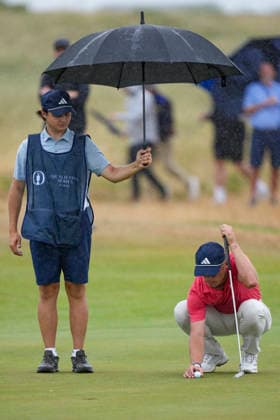 CROSBY, ENGLAND - JUNE 30: Tiger Christensen™s caddy shelters him from the rain while putting on the seventeenth green during round one of the Final Qualifying for The Open Championship at West Lancashire Golf Club, Crosby on June 30, 2026 in Crosby, Merseyside, England The 2026 Open Championship Qualifying