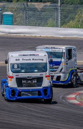 Zwei MAN Renn-Trucks kämpfen in einer engen Kurve am Nürburgring um Position, angeführt von 8 T. Delchambre (SD Truck Racing) vor dem silber-blauen 19 mit DEISEN-Design-Sponsoring. Beide Fahrzeuge sind dicht beieinander auf dem Asphalt der Rennstrecke. MAN Truck Racing 8 (SD Truck Racing) und 19 im Zweikampf am Nürburgring *** Two MAN race trucks battle for position in a tight turn at the Nürburgring, led by the No. 8 T Delchambre SD Truck Racing truck ahead of the silver-and-blue No. 19 truck sponsored by DEISEN Design. Both vehicles are running neck-and-neck on the racetrack’s asphalt. MAN Truck Racing’s No. 8 SD Truck Racing and No. 19 are locked in a duel at the Nürburgring Copyright: xMichaelxSchäferx