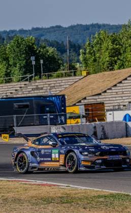 Der Ford Mustang GT3 Evo 1 des Haupt Racing Team durchfährt eine Kurve am Nürburgring in der Sommersonne. Das dunkelblau-goldene Fahrzeug mit Novem Gold-, DEKRA- und Flow Solutions-Logos ist klar erkennbar. Ford Mustang GT3 Evo 1 des Haupt Racing Team am Nürburgring *** The Haupt Racing Team’s Ford Mustang GT3 Evo 1 navigates a turn at the Nürburgring in the summer sun. The dark blue and gold car, featuring the Novem Gold, DEKRA, and Flow Solutions logos, is clearly recognizable. The Haupt Racing Team’s Ford Mustang GT3 Evo 1 at the Nürburgring Copyright: xMichaelxSchäferx