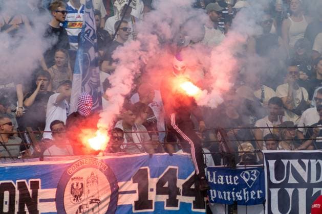 Vermummte Fans des SV Babelsberg 03 brennen im Fanblock rote Bengalos ab und hüllen den Stehplatzbereich in dichten Rauch. Im Vordergrund sind Fangruppenbanner der Ultras sichtbar. Babelsberg-Ultras zünden Pyrotechnik im Karl-Liebknecht-Stadion *** Masked SV Babelsberg 03 fans set off red flares in the fan section, filling the standing-room area with thick smoke. In the foreground, banners from the Ultras fan groups are visible. Babelsberg Ultras set off pyrotechnics at Karl Liebknecht Stadium. Copyright: xspeedshotx xAndreasxTolksdorfx