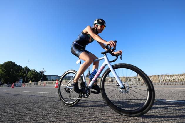 Eine Triathletin fährt auf einem weißen Canyon-Rennrad über eine gesperrte Straße in Hamburg beim Triathlon am Jungfernstieg. Sie trägt einen Helm, Sonnenbrille und einen dunkelblauen Trisuit. Triathletin auf Canyon-Rennrad bei der Radeinheit in Hamburg *** A female triathlete rides a white Canyon road bike down a closed-off street in Hamburg during the Jungfernstieg Triathlon. She is wearing a helmet, sunglasses, and a dark blue trisuit. Female triathlete on a Canyon road bike during a cycling session in Hamburg Copyright: xspeedshotx xSarahxWolfx