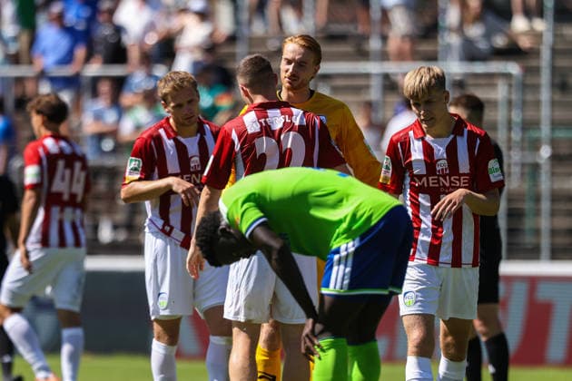 2026.07.11, xkwix, Fußball, Testspiel, FC Gütersloh - FC Schalke 04, NRG24 Stadion im Heidewald, Saison 2026 2027: Guetersloher Spieler jubeln nach Abpfiff im Hintergrund und Christian Gomis (FC Schalke 04 7) enttaeuscht im Vordergrund DFB regulations prohibit any use of photographs as image sequences and or quasi-video. Photo: xKamilxWilkowskixPressefotoKochx Nordrhein-Westfalen Deutschland *** July 11, 2026, xkwix, soccer, friendly match, FC Gütersloh vs. FC Schalke 04, NRG24 Stadium in Heidewald, 2026–2027 season: Gütersloh players celebrate in the background after the final whistle, while Christian Gomis of FC Schalke 04 looks disappointed in the foreground. DFB regulations prohibit any use of photographs as image sequences and or quasi-video. Photo: xKamilxWilkowskixPressefotoKochx North Rhine-Westphalia, Germany