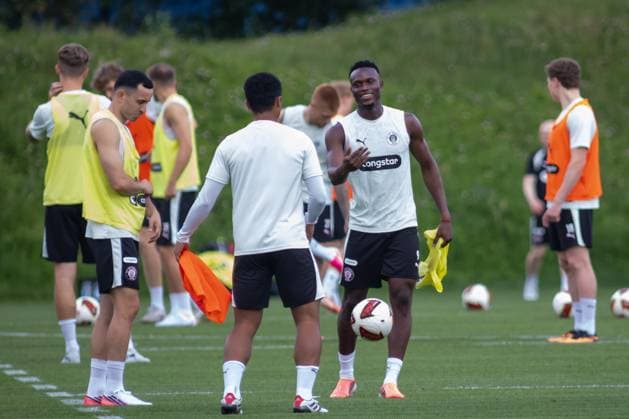 Mehrere Spieler des FC St. Pauli beim Aufwärmen auf dem Trainingsplatz, ein Spieler hält einen Fußball und lacht einem Mitspieler entgegen. Im Hintergrund sind weitere Spieler mit Leibchen zu sehen. FC St. Pauli Spieler beim Training im Trainingszentrum Hamburg *** Several FC St. Pauli players warming up on the practice field; one player is holding a soccer ball and smiling at a teammate. In the background, more players in bibs can be seen. FC St. Pauli players training at the Hamburg training center Copyright: xAndreasxTolksdorfx
