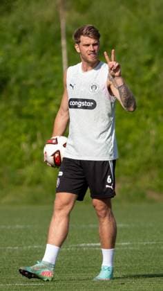 Ein Spieler des FC St. Pauli hält einen Fußball unter dem Arm und zeigt ein Victory-Zeichen in die Kamera. Das Training findet auf dem Rasenplatz des Trainingszentrums in Hamburg statt. Marcus Mathisen ( 6 FC St. Pauli) hat sichtbar gute Laune beim Training und setzt das Peace-Zeichen beim Training in Hamburg *** An FC St. Pauli player holds a soccer ball under his arm and makes a victory sign at the camera. The practice is taking place on the grass field at the training center in Hamburg. Marcus Mathisen (6) of FC St. Pauli is visibly in good spirits during practice and makes the peace sign during practice in Hamburg. Copyright: xAndreasxTolksdorfx