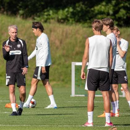 Ein Trainer des FC St. Pauli gibt auf dem Trainingsplatz Anweisungen an eine Gruppe von Spielern. Im Hintergrund ist ein Tor zu sehen, ein Spieler mit der Nummer 42 steht unter den Zuhörern. Co-Trainer Jens Schuster ( js FC St. Pauli) gibt Anweisungen beim FC St. Pauli Training in Hamburg *** A coach from FC St. Pauli is giving instructions to a group of players on the practice field. A goal can be seen in the background; a player wearing number 42 is among those listening. Assistant coach Jens Schuster of FC St. Pauli is giving instructions during an FC St. Pauli practice in Hamburg. Copyright: xAndreasxTolksdorfx
