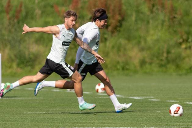 Zwei Spieler des FC St. Pauli liefern sich beim Training im Trainingszentrum in Hamburg einen intensiven Zweikampf um den Ball. Beide sprinten nebeneinander über den Rasen, mehrere Bälle liegen im Hintergrund. Marcus Mathisen und Tomoya Ando im Zweikampf beim Training in Hamburg *** Two FC St. Pauli players are locked in an intense battle for the ball during training at the team s training center in Hamburg. Both are sprinting side by side across the field, with several balls lying in the background. Marcus Mathisen and Tomoya Ando are locked in a battle for the ball during training in Hamburg. Copyright: xAndreasxTolksdorfx