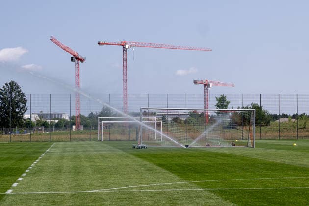Ein Rasensprenger in Aktion auf dem Platz 7 des Campus, im Hintergrund Kraene Baukraene FC Bayern Muenchen Frauen, Fussball, Google Pixel Frauen-Bundesliga, Trainingseinheit, Saison 2026 2027, 16.07.2026. Foto: HMB Media Franz Feiner *** A sprinkler in action on Field 7 of the campus, with FC Bayern Munich Women s construction cranes in the background; soccer, Google Pixel Women s Bundesliga, training session, 2026–2027 season, July 16, 2026; photo by HMB Media, Franz Feiner Copyright: HMBxMedia FranzxFeiner