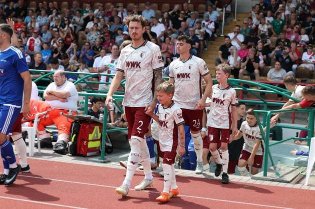 Calvin Brackelmann 2 (FC Augsburg) mit einem Einlaufkind an der Hand, FC Augsburg vs. BFV-Schwaben-Auswahl, Fussball, 1. Bundesliga, Testspiel, Saison 2026 27, 18.07.2026 Augsburg Bayern Deutschland *** Calvin Brackelmann 2 of FC Augsburg holding the hand of a child leading the players onto the field, FC Augsburg vs. BFV Schwaben Select Team, soccer, Bundesliga 1, friendly match, 2026–27 season, July 18, 2026, Augsburg, Bavaria, Germany Copyright: xkolbert-press ChristianxKolbertx