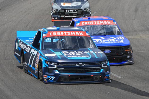 NORTH WILKESBORO, NC - JULY 18: Carson Hocevar ( 77 Spire Motorsports Delaware Life Chevrolet) races Layne Riggs ( 34 Front Row Motorsports Infinite Communications Group Ford) into turn 1 during the running of the NASCAR, Motorsport, USA Craftsman Truck Series FaithFest 250 on July 18, 2026 at North Wilkesboro Speedway in North Wilkesboro, NC. (Photo by Jeff Robinson Icon Sportswire) AUTO: JUL 18 NASCAR CRAFTSMAN Truck Series Faith Fest 250 EDITORIAL USE ONLY Icon26071824651250