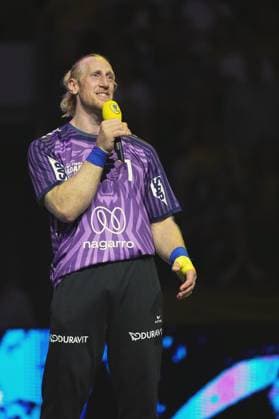 Mikael Appelgren ( 1; Team Apfel) steht mit einem gelben Mikrofon in der Hand auf dem Spielfeld der SAP Arena in Mannheim und lächelt dabei. Er trägt das lila Trikot mit der Nummer 1 sowie blaue und gelbe Bandagen an den Handgelenken. Mikael Appelgren ( 1; Team Apfel) spricht ins Mikrofon in der SAP Arena *** Mikael Appelgren of Team Apfel stands on the court at the SAP Arena in Mannheim, holding a yellow microphone and smiling. He is wearing the purple jersey with the number 1, as well as blue and yellow wristbands. Mikael Appelgren of Team Apfel speaks into the microphoneat the SAP Arena Copyright: xspeedshotx xLukasxTrunkx