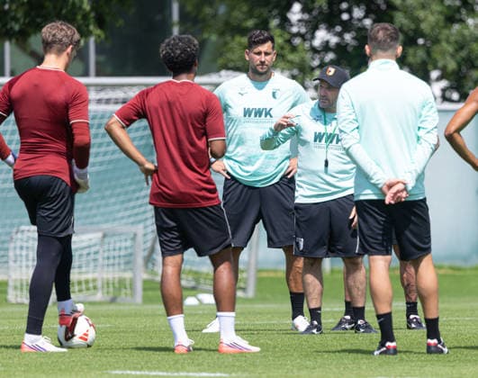 Manuel Baum (Trainer FC Augsburg) spricht mit den Spielern, Philipp Tschauner (Koordinator Torwarttrainer im NLZ) hört zu. FC Augsburg, Training, *** Manuel Baum, head coach of FC Augsburg, talks with the players; Philipp Tschauner, goalkeeper coach coordinator at the NLZ, listens. FC Augsburg, Training,