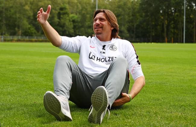 23.07.2026, NED, Fußball, Herren, 1. Bundesliga, Saison 2026 2027, Trainingslager, Rasenplatz, SV Elversberg Vincent Wagner ( Cheftrainer SV Elversberg ) beim Interview mit dem SR Saarländischen Rundfunk, er stellte eine Holzbank weg und setzte sich direkt auf den Rasen, weil das besser findet und es seine Bodenständigkeit und Herzlichkeit besser ausdrückt Stroe Rasenplatz Gelderland Niederlande *** July 23, 2026, NED, Soccer, Men s, 1. Bundesliga, 2026–2027 Season, Training camp, grass field, SV Elversberg Vincent Wagner, head coach of SV Elversberg, during an interview with SR Saarländischer Rundfunk; he moved a wooden bench aside and sat directly on the grass because he thinks it’s better and better expresses his down-to-earth nature and warmth Stroe, grass field, Gelderland, Netherlands Copyright: xNordphotox xSMx