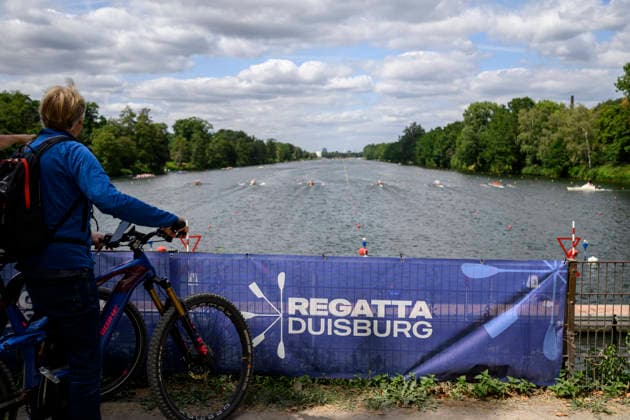 Blick auf die die Regattabahn Duisburg, vom Start aus, ein Fahrradfahrer schaut sich die Wettkämpfe an, Banner Regatta Duisburg, am 23.07.2026 Rudern U-23 Weltmeisterschaft vom 23.07.- 26.07.2026 in Duisburg Deutschland. Regattabahn *** View of the Duisburg regatta course from the starting line; a cyclist watches the races, Banner for the Duisburg Regatta, July 23, 2026: U23 World Rowing Championships, July 23–26, 2026, at the Duisburg Regatta Course in Germany