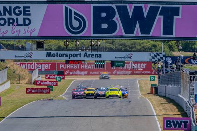 Ein Pulk GT3-Fahrzeuge beim Start, darunter ein neongelb-grüner Porsche 911 GT3 R von Manthey Racing, kämpft auf der Start-Ziel-Geraden der Motorsport Arena Oschersleben um Positionen. Die Rennampel zeigt Grün, im Hintergrund sind die BWT- und Windhager-Streckenbanner sichtbar. GT3-Fahrzeuge passieren die Start-Ziel-Gerade in Oschersleben *** A pack of GT3 cars at the start, including a neon yellow-and-green Porsche 911 GT3 R from Manthey Racing, battles for position on the start-finish straight at the Motorsport Arena Oschersleben. The starting lights turn green, with the BWT and Windhager track banners visible in the background. GT3 cars pass the start-finish straight in Oschersleben Copyright: xMichaelxSchäferx
