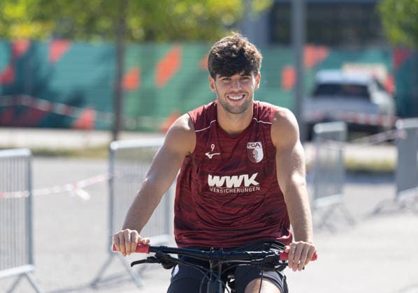 Rodrigo Ribeiro (FC Augsburg 9) gut gelaunt mit dem Fahrrad auf dem Weg zum Trainingsplatz; FC Augsburg, Training, *** Rodrigo Ribeiro, FC Augsburg 9, in good spirits on his bike on the way to the FC Augsburg training field, training,