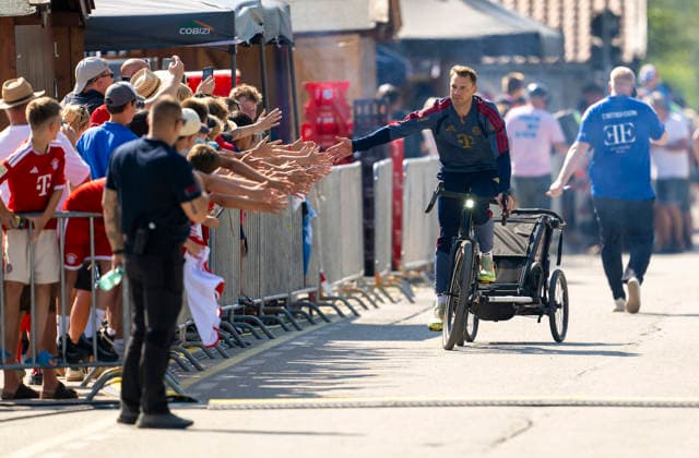 30.07.2026, Fussball Bundesliga 2026 2027, Trainingslager FC Bayern München in Rottach-Egern am Tegernsee (Bayern). Testspiel FC Rottach Egern - FC Bayern München, Torwart Manuel Neuer (FC Bayern München) kommt mit dem Bike und Kinderanhänger am Stadion an. *** July 30, 2026, 2026–2027 Bundesliga, FC Bayern Munich training camp in Rottach Egern on Lake Tegernsee, Bavaria; friendly match between FC Rottach Egern and FC Bayern Munich; goalkeeper Manuel Neuer of FC Bayern Munich arrives at the stadium by bike with a child trailer