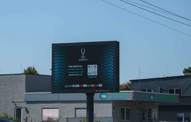 Österreich: Fußball UEFA Super Cup 2026, Finale, Paris Saint-Germain vs Aston Villa FC, Salzburg: Eine digitale Anzeigetafel wirbt in Salzburg für das UEFA Super Cup Fan Festival mit Veranstaltungszeiten und QR-Code. Die Aufnahme entstand am Spieltag des UEFA Super Cup Finales 2026 zwischen Paris Saint-Germain und Aston Villa FC und zeigt die Eventkommunikation im Stadtgebiet vor dem Anpfiff. *** Austria Soccer UEFA Super Cup 2026, Final, Paris Saint-Germain vs. Aston Villa FC, Salzburg: A digital scoreboard in Salzburg promotes the UEFA Super Cup Fan Festival with event times and a QR code. The photo was taken on the day of the 2026 UEFA Super Cup Final between Paris Saint-Germain and Aston Villa FC and shows the event signage throughout the city before kickoff. Copyright: xAymanxAlahmedx