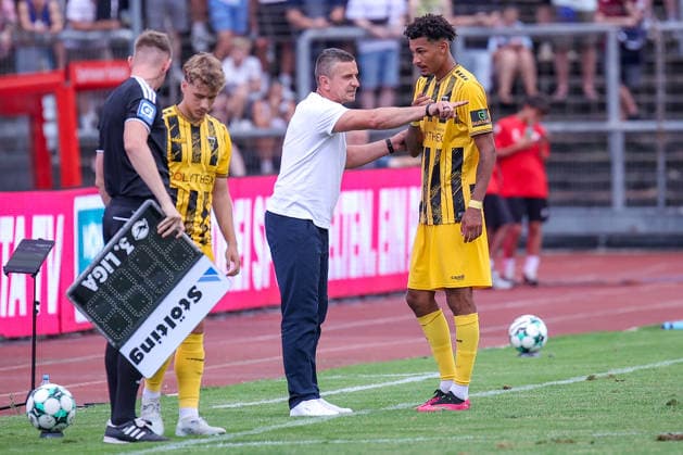 15.08.2026, xsefx, Fußball, SC Fortuna Köln - TSV Alemannia Aachen, 3.Liga, Südstation, 2. Spieltag, Saison 2026 2027: Cheftrainer Mersad Selimbegovic (Alemannia Aachen hc) gestikulierend am Spielfeldrand neben Joel da Silva Kiala (Alemannia Aachen 37) DFB regulations prohibit any use of photographs as image sequences and or quasi-video. Nordrhein-Westfalen Deutschland *** August 15, 2026, xsefx, Soccer, SC Fortuna Köln vs. TSV Alemannia Aachen, 3rd Division, Südstation, Matchday 2, 2026–2027 season Head coach Mersad Selimbegovic of Alemannia Aachen gesturing on the sideline next to Joel da Silva Kiala Alemannia Aachen 37 DFB regulations prohibit any use of photographs as image sequences and or quasi-video North Rhine-Westphalia, Germany