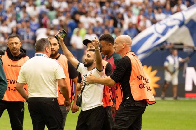 16.08.2026: Fußball: FC Schalke 04 - Real Madrid, Testspiel in der Veltins Arena Gelsenkirchen. Real Madrid Fan rennt nach dem Anpfiff aufs Feld für ein Selfie mit Kylian Mbappe (Real Madrid, 10) und wird von der Security nach dem Selfie abgefangen und abgeführt. WICHTIGER HINWEIS: Gemäß den Vorgaben der DFL und des DFB ist es untersagt, in dem Stadion und oder vom Spiel angefertigte Fotoaufnahmen in Form von Sequenzbildern und oder videoähnlichen Fotostrecken zu verwerten bzw. verwerten zu lassen. *** August 16, 2026: Soccer – FC Schalke 04 vs. Real Madrid, friendly match at the Veltins Arena in Gelsenkirchen. A Real Madrid fan runs onto the field after the kickoff to take a selfie with Kylian Mbappé of Real Madrid, 10 and is intercepted by security after the selfie and escorted off the field IMPORTANT NOTICE In accordance with the guidelines of the DFL and the DFB, it is prohibited to to use or allow the use of photographs taken in the stadium and or during the game in the form of sequential images and or video-like photo series Copyright: xJamesxZabelx