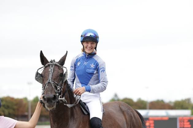Eine lächelnde Jockeyrin in blau-weißem Dress und blauem Helm sitzt nach dem Rennen auf ihrem dunklen Pferd. Im Hintergrund ist die Anzeigetafel der Rennbahn Berlin Mariendorf zu sehen. Jockeyrin nach dem Rennen auf ihrem Pferd in Mariendorf *** A smiling female jockey in a blue-and-white outfit and a blue helmet is sitting on her dark horse after the race. In the background, the scoreboard at the Berlin-Mariendorf Racetrack can be seen. Female jockey on her horse after the race in Mariendorf Copyright: xspeedshotx