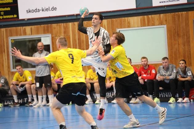 Domen Makuc ( 35; THW Kiel) springt hoch und hält den Ball zur Wurfvorbereitung, während zwei Spieler des TSV Altenholz – darunter 9 – ihn in der Luft stellen. Im Hintergrund verfolgen Ersatzspieler und Offizielle beider Teams die Szene von der Bank. Domen Makuc ( 35; THW Kiel) springt zum Wurf zwischen zwei Altenholz-Abwehrspielern *** Domen Makuc, No. 35 of THW Kiel, jumps high and holds the ball in preparation for a shot, while two TSV Altenholz players—including No. 9 —block him in midair. In the background, substitutes and officials from both teams watch the action from the bench. Domen Makuc (No. 35) of THW Kiel jumps to take a shot between two Altenholz defenders Copyright: xspeedshotx