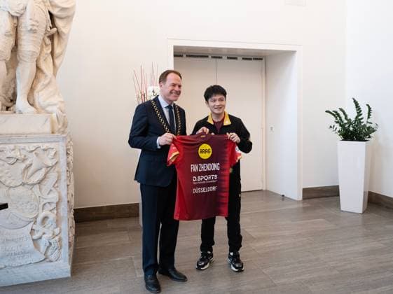 (260820) -- DUSSELDORF, Aug. 20, 2026 -- Fan Zhendong (R) gives his jersey to Stephan Keller, mayor of Dusseldorf, during the welcoming ceremony in Dusseldorf, Germany, Aug. 20, 2026. Chinese Table tennis, Tischtennis star Fan Zhendong was officially unveiled by his new club Borussia Dusseldorf at a press conference, PK, Pressekonferenz here on Thursday, as the Olympic champion prepares for his second season in the German Table Tennis Bundesliga and another campaign in European competition. ) (SP)GERMANY-DUSSELDORF-TABLE TENNIS-FAN ZHENDONG-CEREMONY ZhangxHaofu 