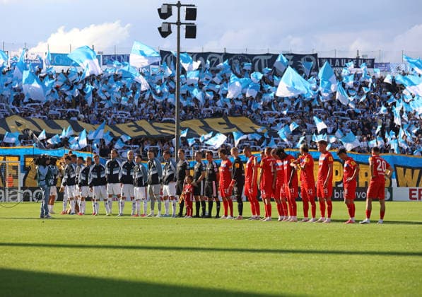 Fussball, Herren, DFB-Pokal, 1.Hauptrunde, Saison 2026 2027, TSV 1860 München - Holstein Kiel, Grünwalder Stadion Einlaufen beider Teams mit der Choreo der 60er Fans in der Westkurve im Hintergrund *** Soccer, Men s, DFB Cup, First Round, 2026–2027 Season, TSV 1860 Munich vs. Holstein Kiel, Grünwalder Stadium: Both teams take the field with the 60s fans’ choreographed display in the West Stand in the background