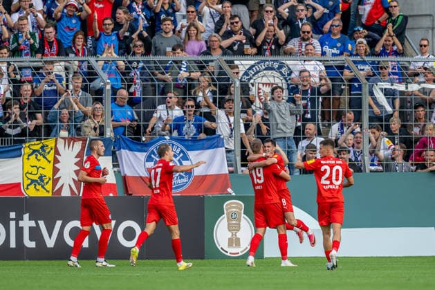 Die Kieler bejubeln vor der eigenen Fankurve mit Phil Harres (Holstein Kiel, 19) dessen Tor zum 0:1 GER, TSV 1860 Muenchen vs. Holstein Kiel, Fussball, DFB-Pokal, 1. Runde, Saison 2026 2027, 22.08.2026. (DFL DFB REGULATIONS PROHIBIT ANY USE OF PHOTOGRAPHS as IMAGE SEQUENCES and or QUASI-VIDEO). Foto: HMB Media Heike Feiner *** Kiel fans cheer in front of their own fan section as Phil Harre of Holstein Kiel, 19, scores the 0-1 goal (GER), TSV 1860 Munich vs. Holstein Kiel, Soccer, DFB Cup, 1st Round, 2026-2027 Season, August 22, 2026 DFL DFB regulations prohibit any use of photographs as image sequences and or quasi-video. Photo: HMB Media, Heike Feiner Copyright: HMBxMedia HeikexFeiner