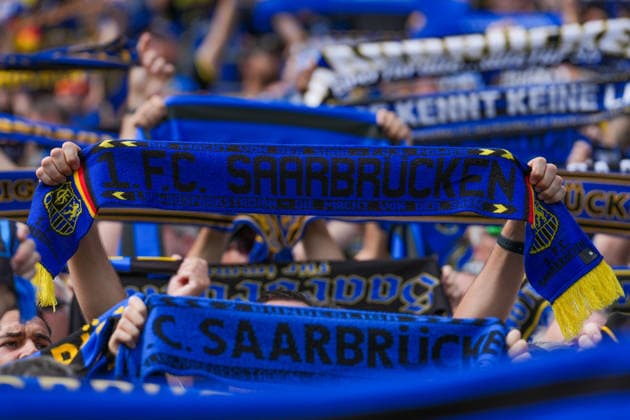 22.08.2026, xydrx, Fußball, DFB Pokal, 1. FC Saarbrücken - Hertha BSC, Saison 2026 2027, Ludwigsparkstadion: Ein Fan des 1.FC Saarbruecken hält einen Schal hoch DFB regulations prohibit any use of photographs as image sequences and or quasi-video. *** August 22, 2026, xydrx, Soccer, DFB Cup, 1 FC Saarbrücken vs. Hertha BSC, 2026–2027 season, Ludwigsparkstadion A fan of 1 FC Saarbrücken holds up a scarf. DFB regulations prohibit any use of photographs as image sequences and or quasi-video. Copyright: HMBxMedia YannisxDreimann