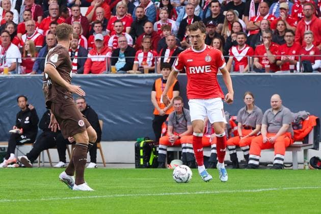 Noah Pesch ( 11; Rot-Weiss Essen) treibt den Ball am Seitenrand des Stadions an der Hafenstraße, während ein Spieler des FC St. Pauli den Weg versperrt. Im Hintergrund verfolgen zahlreiche Rot-Weiss-Fans die Szene. Noah Pesch ( 11; Rot-Weiss Essen) im Zweikampf gegen FC St. Pauli *** Noah Pesch, No. 11 for Rot-Weiss Essen, drives the ball along the sideline at the stadium on Hafenstraße, while an FC St. Pauli player blocks his path. In the background, numerous Rot-Weiss fans watch the action. Noah Pesch, No. 11 for Rot-Weiss Essen, battles for the ball against FC St. Pauli. Copyright: xRuhr.Pottraitx