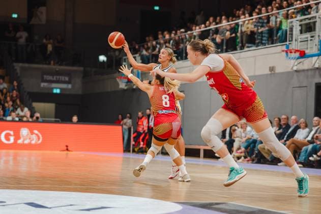 Eine Spielerin Deutschlands zieht zum Korbleger hoch, während Eszter Rátkai ( 8; Hungary) von hinten verteidigt und eine weitere ungarische Spielerin den Weg versperrt. Die Szene entfaltet sich vor gut besetzten Tribünen der Sparkassen-Arena in Göttingen. Eszter Rátkai ( 8; Hungary) und Deutschland im Zweikampf unter dem Korb *** A German player drives toward the basket for a layup, while Eszter Rátkai (No. 8, Hungary) defends from behind and another Hungarian player blocks her path. The scene unfolds before a well-attended crowd at the Sparkassen Arena in Göttingen. Eszter Rátkai (No. 8, Hungary) and a German player go head-to-head under the basket. Copyright: xJoelxKruehlerx