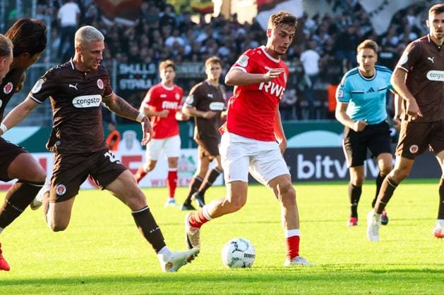Marvin Obuz von Rot-Weiss Essen setzt sich mit dem Ball gegen Louis Oppie vom FC St. Pauli durch. Im Hintergrund begleitet ein Schiedsrichter die Szene, die Tribünen des Stadions an der Hafenstraße sind gut gefüllt. Marvin Obuz (Rot-Weiss Essen) im Zweikampf gegen Louis Oppie (FC St. Pauli) *** Marvin Obuz of Rot Weiss Essen wins the ball from Louis Oppie of FC St. Pauli. In the background, a referee oversees the play; the stands at the stadium on Hafenstraße are well-filled. Marvin Obuz of Rot Weiss Essen in a duel with Louis Oppie of FC St. Pauli. Copyright: xRuhr.Pottraitx