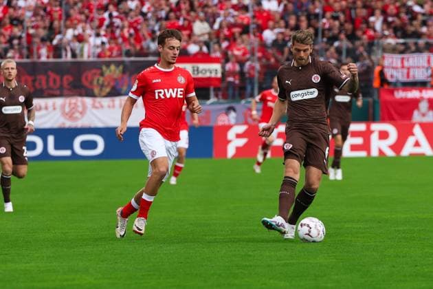 Marvin Obuz von Rot-Weiss Essen setzt Marcus Mathisen vom FC St. Pauli im Mittelfeld unter Druck, während Mathisen den Ball am Fuß führt. Im Hintergrund feuern die Essener Fans lautstark ihre Mannschaft an. Marvin Obuz (Rot-Weiss Essen) im Zweikampf mit Marcus Mathisen (FC St. Pauli) *** Marvin Obuz of Rot Weiss Essen puts pressure on Marcus Mathisen of FC St. Pauli in midfield while Mathisen dribbles the ball. In the background, the Essen fans are loudly cheering on their team. Marvin Obuz of Rot Weiss Essen battles for the ball with Marcus Mathisen of FC St. Pauli. Copyright: xRuhr.Pottraitx