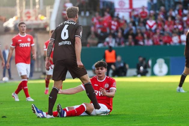 Jaka Cuber Potocnik ( 9; Rot-Weiss Essen) sitzt nach einem Zweikampf auf dem Rasen und blickt auf, während ein Spieler des FC St. Pauli mit der Rückennummer 6 (Mathisen) über ihn hinwegsteht. Im Hintergrund verfolgen weitere Spieler und die Zuschauer im Stadion an der Hafenstraße die Szene. Jaka Cuber Potocnik ( 9; Rot-Weiss Essen) am Boden nach Zweikampf *** Jaka Cuber Potocnik, No. 9 for Rot-Weiss Essen, is sitting on the field after a tackle and looks up, while an FC St. Pauli player wearing jersey number 6, Mathisen, stands over him. In the background, other players and spectators at the Hafenstraße stadium watch the scene unfold. Jaka Cuber Potocnik (No. 9, Rot Weiss Essen) is on the ground after a tackle. Copyright: xRuhr.Pottraitx