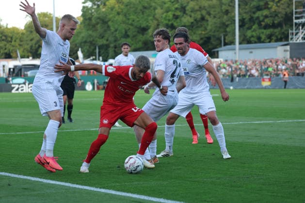 BERLIN, GERMANY - AUGUST 24: Muhammed Damar (Wolfsburg, 20) in the duel for the ball with Lennart Czyborra (VSG Altglienicke, 3) and Jonas Hartl (VSG Altglienicke, 21), during the DFB Cup DFB Pokal match (Round 1) between DFB-Pokal: VSG Altglienicke - VfL Wolfsburg at Stadion auf dem Wurfplatz (Amateurstadion im Olympiapark) on August 24, 2026 in Berlin, Germany. DFL REGULATIONS PROHIBIT ANY USE OF PHOTOGRAPHS AS IMAGE SEQUENCES AND OR QUASI-VIDEO. Berlin Germany Copyright: xO.Frankex