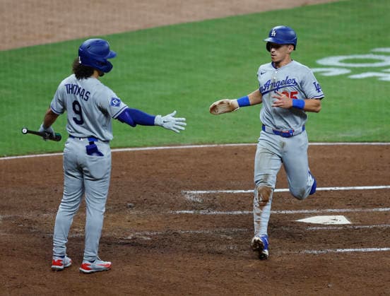 Second baseman Tommy Edman 25 of the Los Angeles Dodgers shakes hands with centerfielder Alex Thomas 9 after scoring in the fourth inning against the Atlanta Braves at Truist Park on Tuesday, August 25, 2026 in Atlanta, Georgia.  ATL20260825112 MikexZarrilli