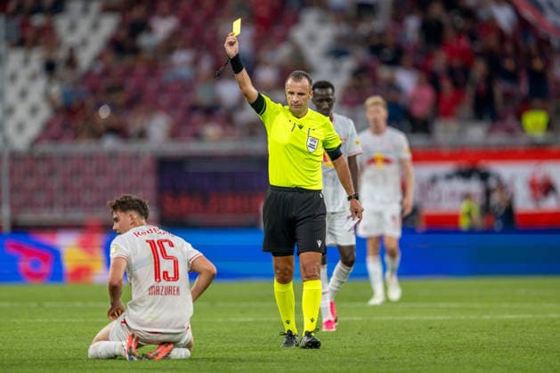 SOCCER - UEFA EL, RBS vs Mjaellby SALZBURG,AUSTRIA,27.AUG.26 - SOCCER - UEFA Europa League, play-off, Red Bull Salzburg vs Mjaellby AIF. Image shows referee Irfan Peljto and Bartosz Mazurek (RBS). Keyword: yellow card  GEPAxpictures xWolfgangxKofler