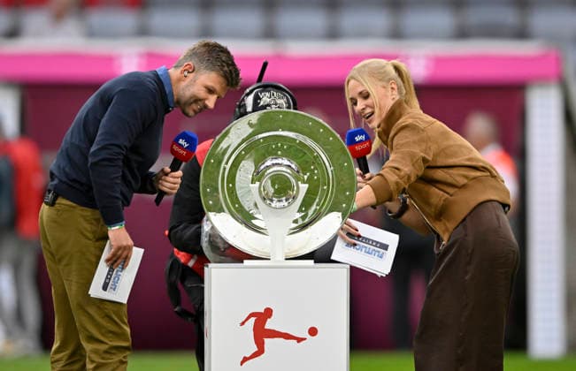 vor Spielbeginn: SKY Moderatorin Reporterin vor Meisterschale Schale mit TV-Experte Thomas Hitzlsperger FC Bayern Muenchen FCB vs VfB Stuttgart 28.08.2026 DFL REGULATIONS PROHIBIT ANY USE OF PHOTOGRAPHS AS IMAGE SEQUENCES AND OR QUASI-VIDEO FC Bayern Muenchen FCB vs VfB Stuttgart *** Before the game begins: SKY host and reporter in front of the championship trophy with TV expert Thomas Hitzlsperger—FC Bayern Munich (FCB) vs. VfB Stuttgart, August 28, 2026. DFL regulations prohibit any use of photographs as image sequences and OR QUASI-VIDEO: FC Bayern Munich (FCB) vs. VfB Stuttgart