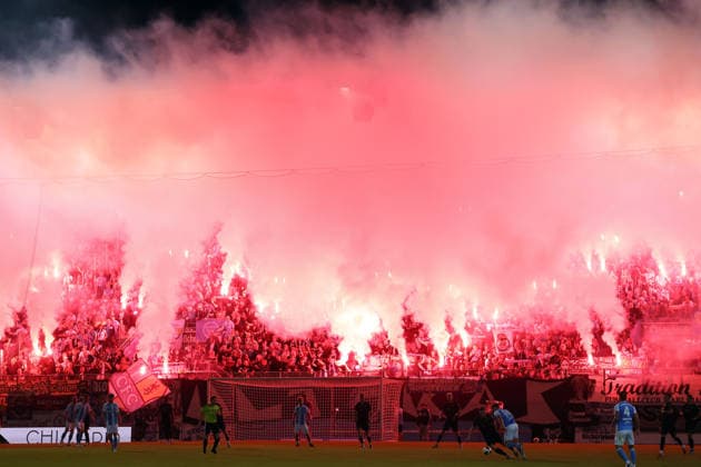 White and red smoke from numerous Bengal flares drifts over the penalty area and the home team’s south stand at the Eins Stadium on Gellertstrasse in Chemnitz shortly before the start of the second half, The Chemnitz players are back on the field: Chemnitzer FC vs. Carl Zeiss Jena, Matchday 7, 2026–27 Northeast Regional League, Saxony, Germany, August 28, 2026, high-risk match,