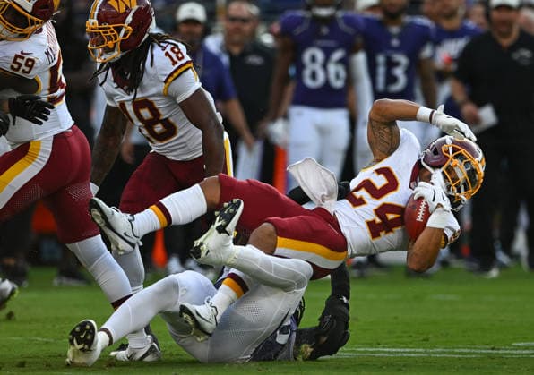 Washington Commanders running back Craig Reynolds (24) is tackled by the Baltimore Ravens defense during the first quarter of a preseason game at M&T Bank Stadium in Baltimore, Maryland, on Friday, August 28, 2026.  BAL20260828103 DAVIDxTULIS