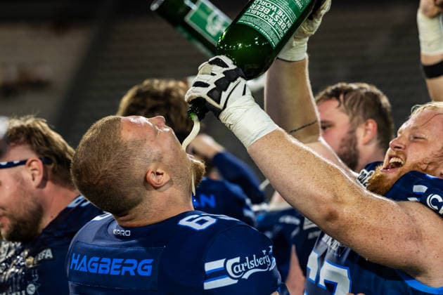 Rasmus Hagberg drinks beer poured from a bottle by a teammate during a postgame celebration. 29.08.2026, Innsbruck, European Football Alliance, Championship Game, Munich Ravens - Nordic Storm. Innsbruck Tivoli Stadium Austria Copyright: xPFA RicoxDoninellix