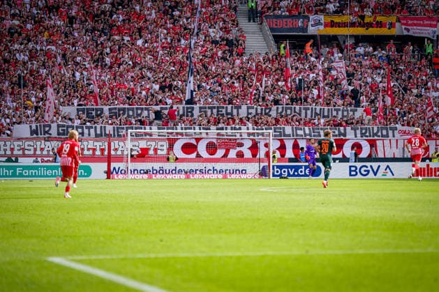 Deutschland: Fussball Bundesliga Saison 2026 - 2027, 1. Spieltag - SC Freiburg vs Werder Bremen - Europa Park Stadion (Freiburg): Banner Tribüne DER SPORTCLUB STEHT FÜR KONTINUITÄT - WIR GRATULIEREN ERNEUT ZUM HÄSSLICHSTEN TRIKOT Spruchband, Transparent, Protestbanner, Fans, Ultras, SC Freiburg, Fankurve, Trikot, Kritik, Fanprotest, Vereinsführung, Kontinuität, Trikotdesign *** Germany Soccer Bundesliga Season 2026–2027, Matchday 1: SC Freiburg vs. Werder Bremen, Europa-Park Stadium, Freiburg, Banner in the stands: THE CLUB STANDS FOR CONTINUITY—ONCE AGAIN, CONGRATULATIONS ON THE UGLIEST JERSEY —banner, protest banner, fans, ultras, SC Freiburg, fan section, jersey, criticism, fan protest, club management, continuity, jersey design Copyright: xJOERANxSTEINSIEKx