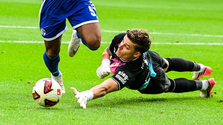 30.08.2026, GER, Fußball, Herren, 1. Bundesliga, FC Augsburg vs FC Schalke 04 Finn Dahmen (FC Augsburg, 1) wirft sich in den Angriff von Moussa Sylla (Schalke, 9) Augsburg WWK-Arena Bayern Deutschland *** August 30, 2026, GER, Soccer, Men s, Bundesliga 1, FC Augsburg vs. FC Schalke 04; Finn Dahmen (FC Augsburg, 1) throws himself into a tackle against Moussa Sylla (Schalke, 9); Augsburg WWK Arena, Bavaria, Germany Copyright: xNordphotox xHafnerx