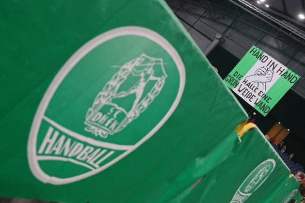 Handball, HBL2 SC DHfK Leipzig vs. GWD Minden, August 31, 2026. Fan banner with the slogan HAND IN HAND, THE ARENA—A GREEN AND WHITE WALL. In front of it, a large coat of arms of SC DHfK Leipzig. Symbolic image, feature, team spirit, handball, 2nd Bundesliga, 2026–2027 season, Matchday 1: SC DHfK Leipzig vs. GWD Minden on August 31, 2026, at the Quarterback Immobilien Arena Leipzig Copyright: xBEAUTIFULxSPORTS JanxKaeferx