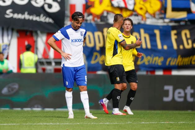 September 5, 2026, Hänsch Arena, Meppen, GER, 3. Liga, Matchday 4: SV Meppen vs. 1. FC Saarbrücken, Ersin Zehir of SV Meppen is frustrated after the 1–5 loss; the Saarland team celebrates in the background. DFL REGULATIONS PROHIBIT ANY USE OF PHOTOGRAPHS AS IMAGE SEQUENCES AND OR QUASI-VIDEO. Meppen, Lower Saxony, Hänsch Arena