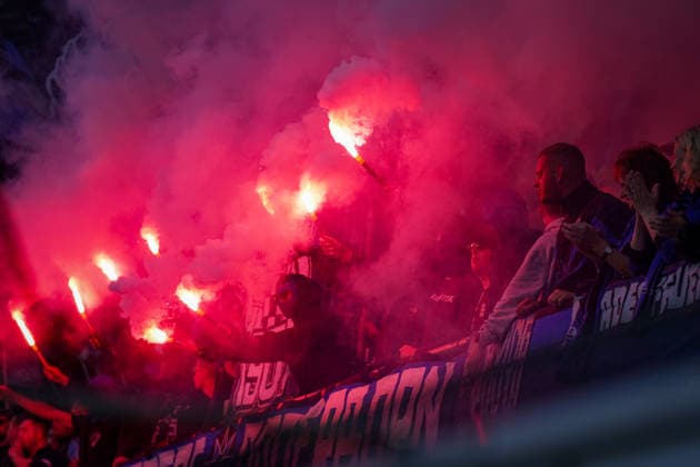 Sport Bilder des Tages Deutschland: Fussball Bundesliga 2026 - 2027, 2. Spieltag - SC Paderborn 07 vs SC Freiburg - Home-Deluxe-Arena (Paderborn): Zuschauer, Fans auf der Tribüne mit brennender roter Pyrotechnik und Bengalos. Dichter roter Rauch über dem Fanblock, mehrere Fans halten Leuchtfackeln in den Händen. Fahnen und Transparente im Zuschauerbereich. *** Germany Soccer Bundesliga 2026–2027, Matchday 2: SC Paderborn 07 vs. SC Freiburg at Home Deluxe Arena in Paderborn; spectators and fans in the stands with burning red pyrotechnics and flares; thick red smoke above the fan section; several fans holding torches; flags and banners in the spectator area Copyright: xJOERANxSTEINSIEKx