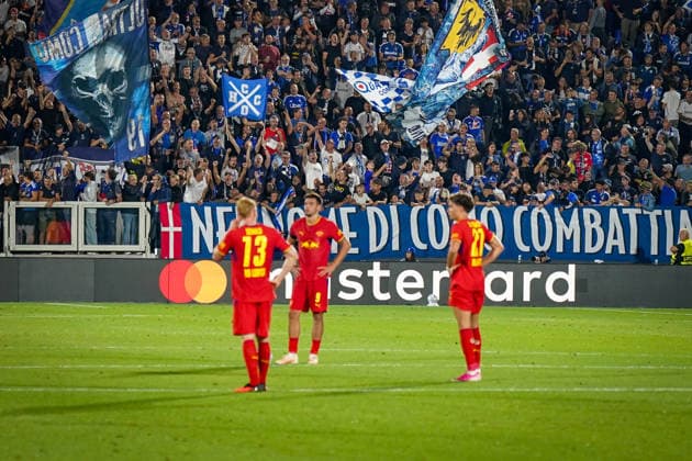 Italy Soccer UEFA Champions League 2026–2027, Matchday 1: Como 1907 vs. RB Leipzig, Giuseppe Sinigaglia Stadium, Como. Como 1907 fans celebrate loudly in the stands behind RB Leipzig players. Large flags and a banner reading NEL NOME DI COMO COMBATTI. Soccer, Champions League, Como 1907, RB Leipzig, Fans, Spectators, Stands, Fan Section, Fan Culture, Home Fans, Flags, Banners, Slogans, Atmosphere, Emotions, Mastercard, Advertising Copyright: xJOERANxSTEINSIEKx