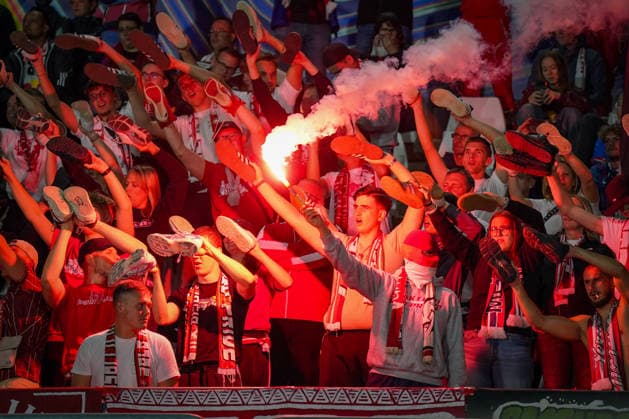 Italy Soccer UEFA Champions League 2026–2027, Matchday 1: Como 1907 vs. RB Leipzig at Giuseppe Sinigaglia Stadium. Como: RB Leipzig fans in the visitors’ section hold their shoes aloft during a choreographed display, while a fan lights a Bengalo pyrotechnic. Soccer, Champions League, RB Leipzig, away fans, spectators, fans, ultras, fan culture, fan choreography, choreography, pyrotechnics, Bengalo, smoke, visitors’ section, fan block, atmosphere, emotions Copyright: xJOERANxSTEINSIEKx