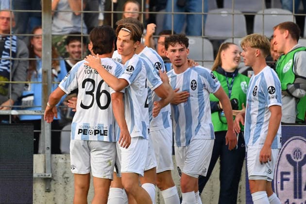 Collective celebration surrounding goal scorer Lance FIEDLER of TSV 1860 Munich after scoring the 1-0 goal, Celebration, joy, excitement, action—Bavarian Regional League soccer, 2026–2027 season, Matchday 8: TSV 1860 Munich vs. Schwaben Augsburg on September 11, 2026, at Grünwalder Stadium in Munich