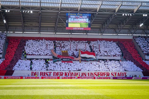 Deutschland: Fussball Bundesliga 2026 - 2027, 3. Spieltag - SC Freiburg vs Borussia Mönchengladbach - Europa-Park-Stadion (Freiburg): Choreographie der Fans des SC Freiburg auf der Südtribüne im Europa-Park Stadion: rot-weißes Fahnenbild mit Freiburger Stadtwappen und Spruchband Du bist der König in unserer Stadt. Fans, Ultras, Zuschauer, Tribüne, Fankurve, Fanchoreo, Choreographie, SC Freiburg, Freiburg, Stadion, Innenansicht, Totale, Anzeigetafel. *** Germany Soccer Bundesliga 2026–2027, Matchday 3: SC Freiburg vs. Borussia Mönchengladbach at Europa-Park Stadium in Freiburg. Choreography by SC Freiburg fans in the South Stand at Europa-Park Stadium: a red-and-white flag display featuring the Freiburg city coat of arms and a banner reading You are the king in our city. Fans, ultras, spectators, stands, fan section, fan choreography, SC Freiburg, Freiburg, stadium, interior view, wide shot, scoreboard Copyright: xJOERANxSTEINSIEKx